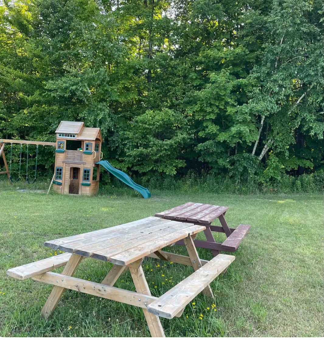 Grassy backyard with wooden playground and picnic table